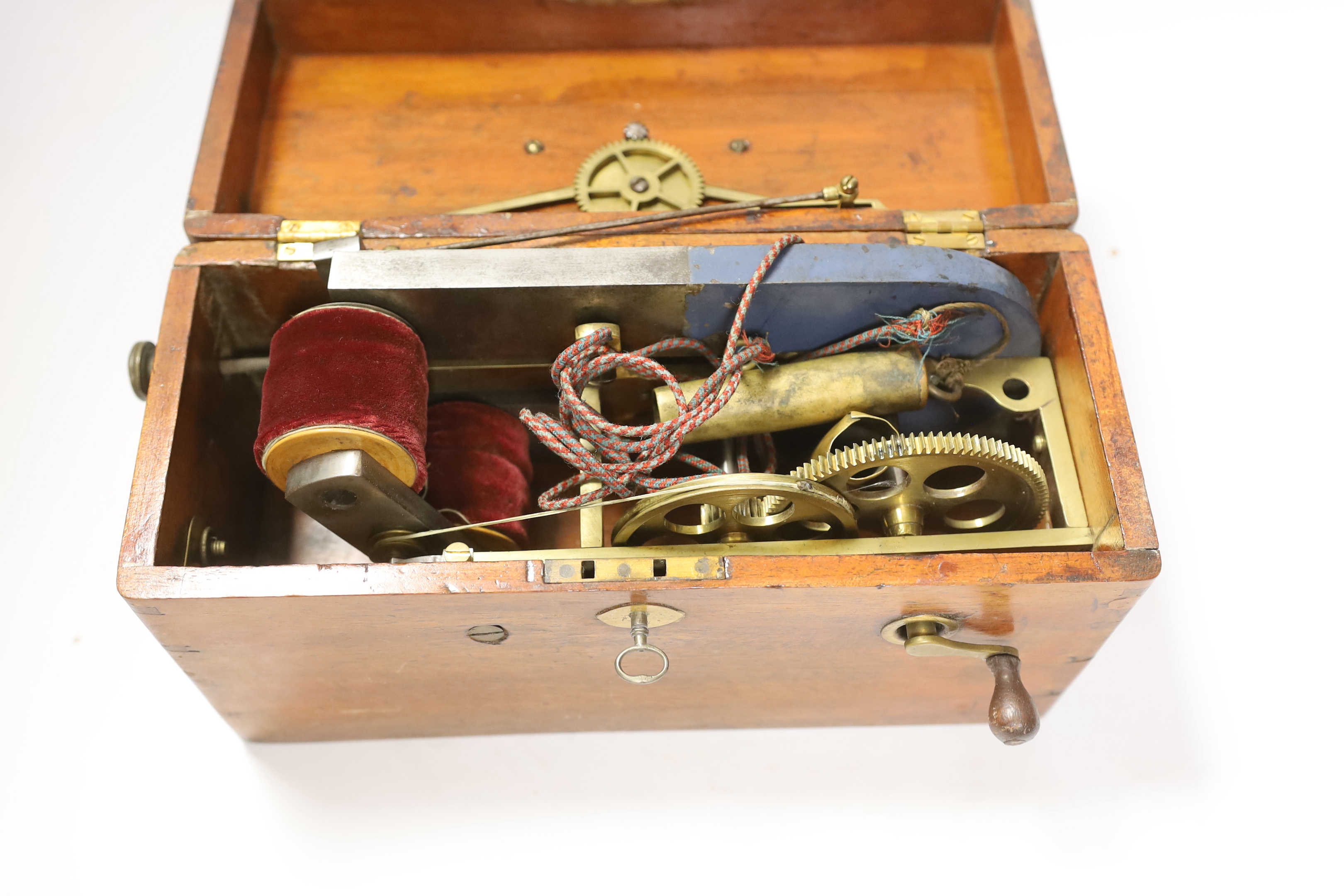 A Magneto electric shock machine in a mahogany case with output gauge to lid and built-in drawer containing a range of alternative fittings and implements with ebonised handles, lock with original key, 16.5cm high, 30cm